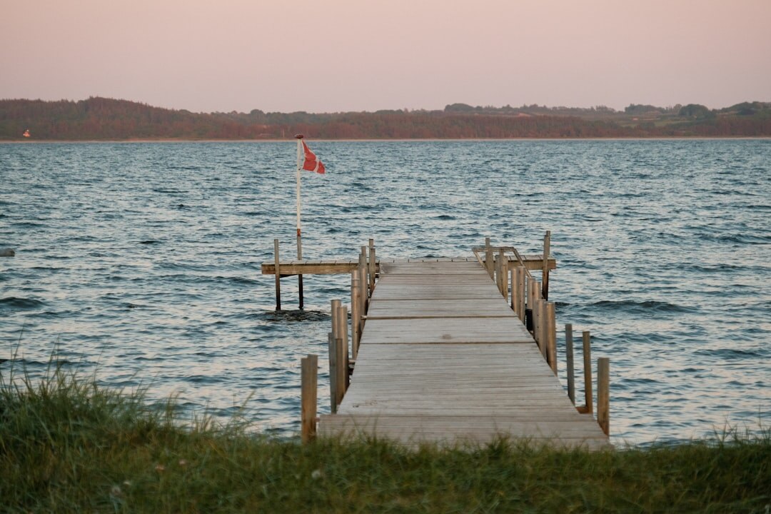 Empty pier stretching into calm sea at dusk in Denmark